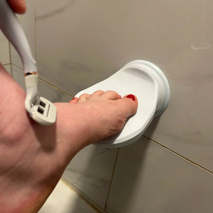 Close-up of a person's foot using the Shave Aid Shower Foot Rest & shaving - Shave Aid