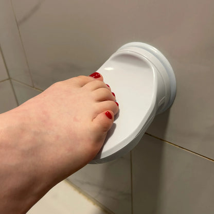 Shave Aid Shower Foot Rest attached to bathroom tiles with a foot placed on it - Shave Aid